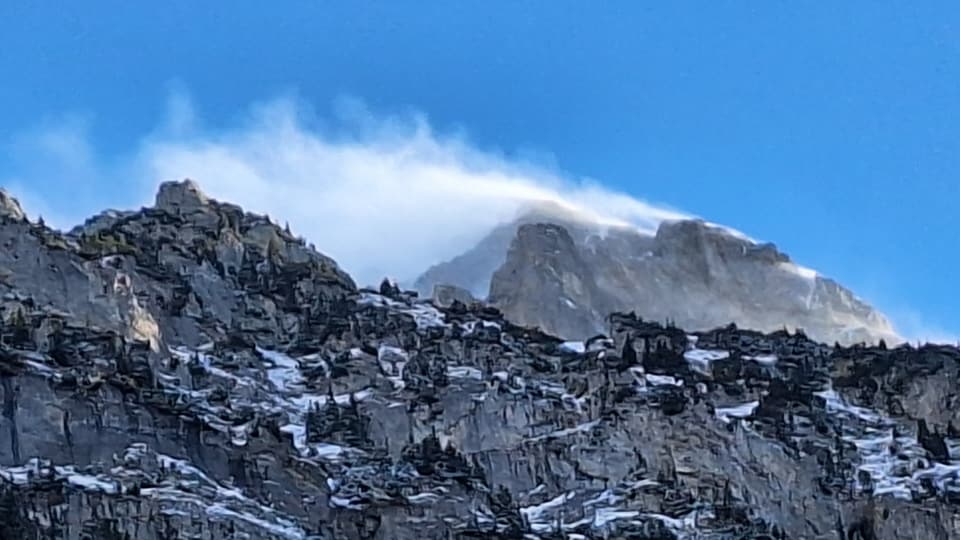 Ältester Urner Schnee wird vom Föhn über einen Berg geblasen.