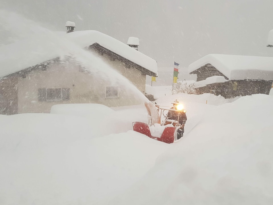 Mann mit Schneeschleuder schaufelt einen Weg frei.