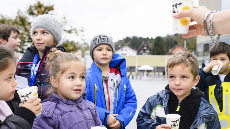 Kinder trinken an einem Herbsttag Milch aus Pappbechern