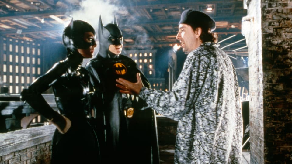 Auf dem Bild sind der Regisseur Tim Burton und die Schauspieler Michelle Pfeiffer und Michael Kaeton in ihren Kostümen zu sehen.
