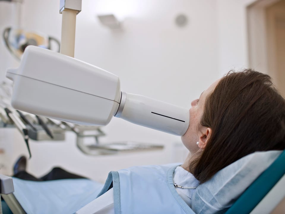 Eine Patientin wird beim Zahnarzt geröntgt.