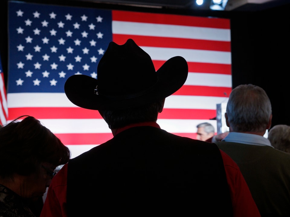 Mann mit Cowboyhut vor einer USA-Flagge