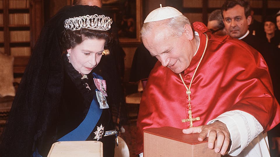 Queen Elizabeth und Papst Johannes Paul gucken sich etwas an.