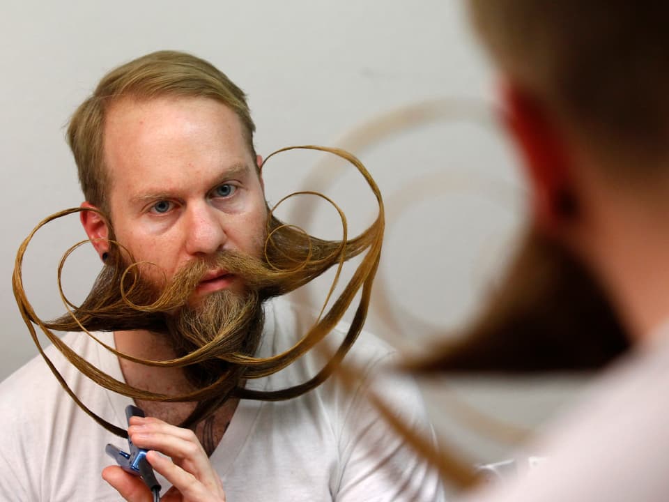Ein Mann frisiert seinen Bart.