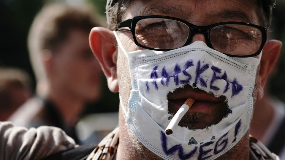 Ein Mann mit einer zerschnittenen Maske und einer Zigarette