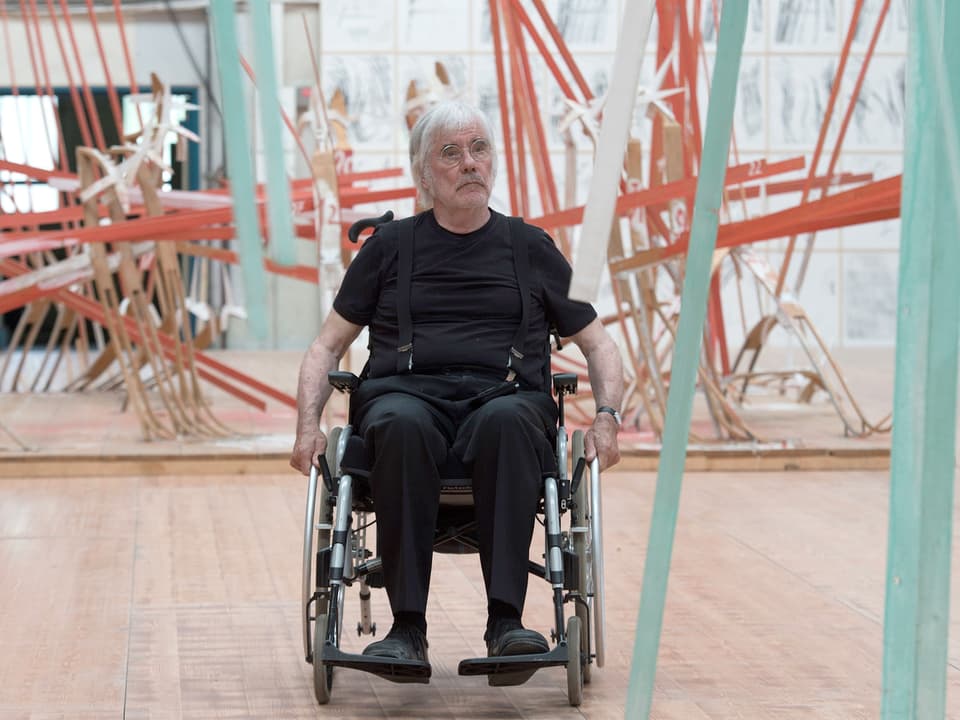 Der Künstler im Rollstuhl inmitten seiner Skulpturen in der Ausstellung.
