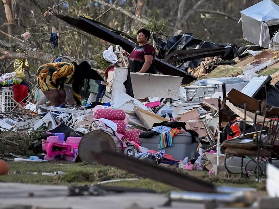 Menschen durchsuchen zerstörtes Haus.