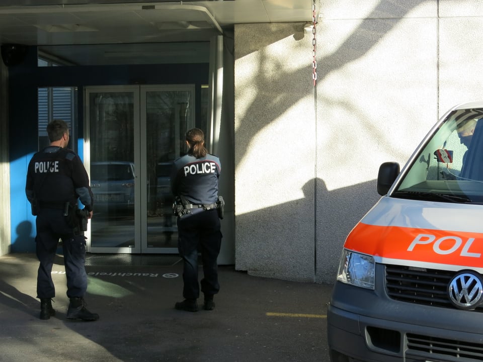 Zwei Polizisten stehen vor einer Eingangstüre.