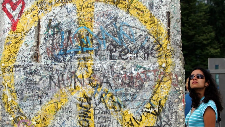 Ein gelbes Peace-Zeichen auf der Berliner Mauer.