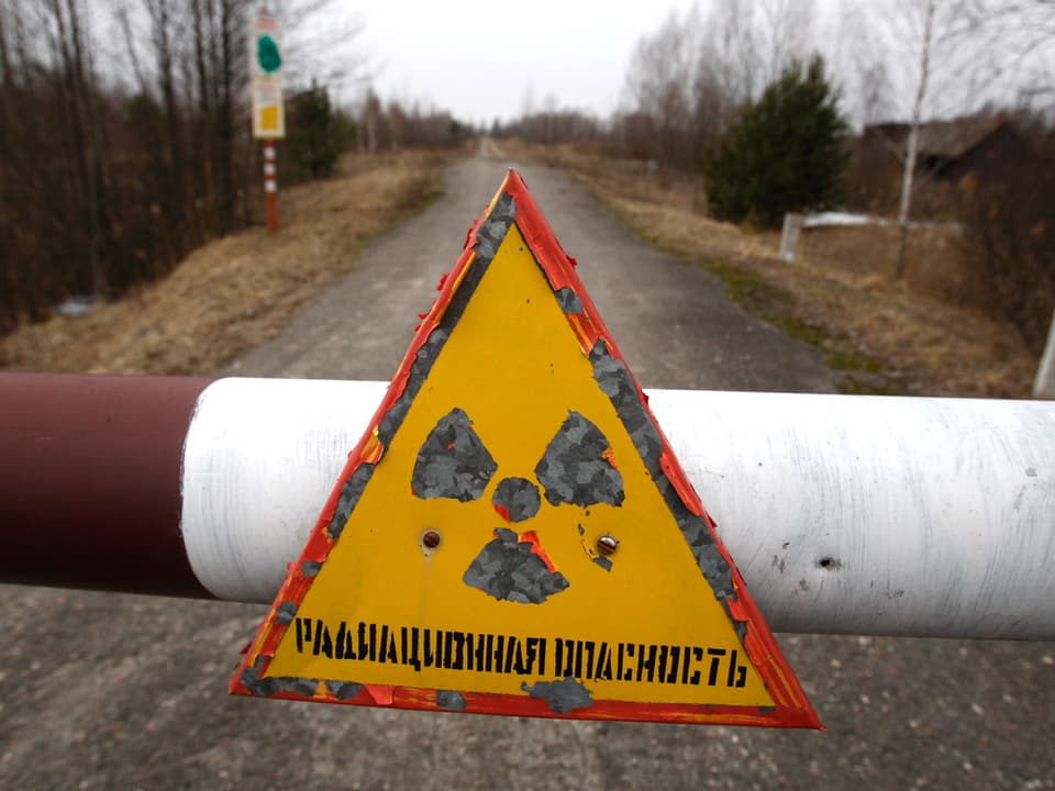 Ein Schild in der Nähe der Sperrzone von Tschernobyl wart vor radioaktiver Strahlung.