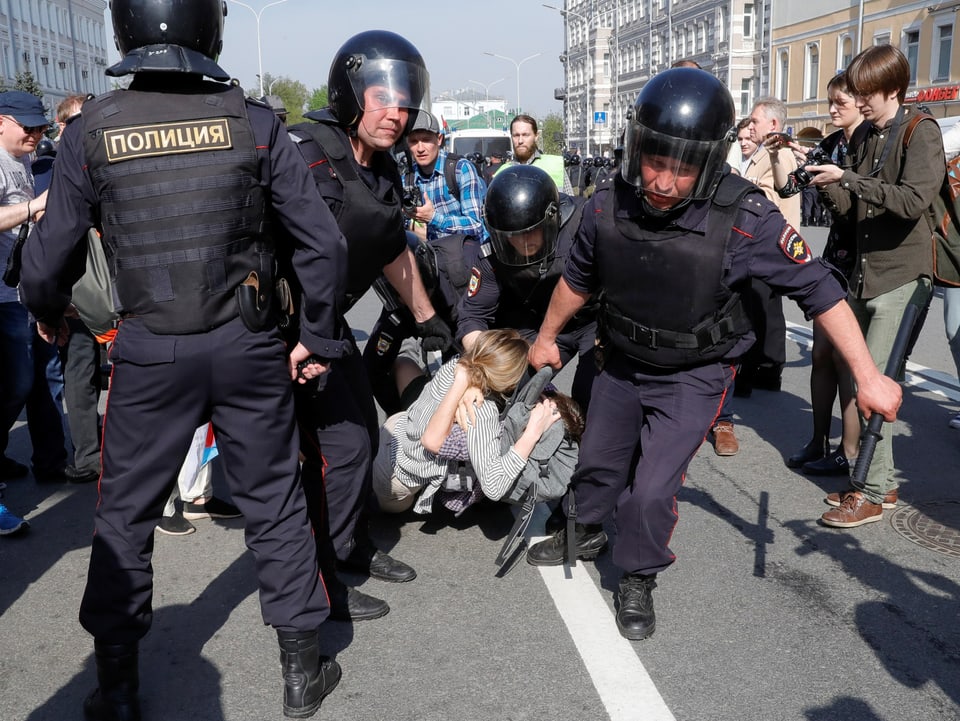 Vier Polizisten schleppen zwei Frauen weg an einer Demonstration in Moskau, Russland.