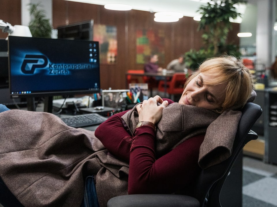 Eine Frau schläft an ihrem Arbeitsplatz im Stuhl