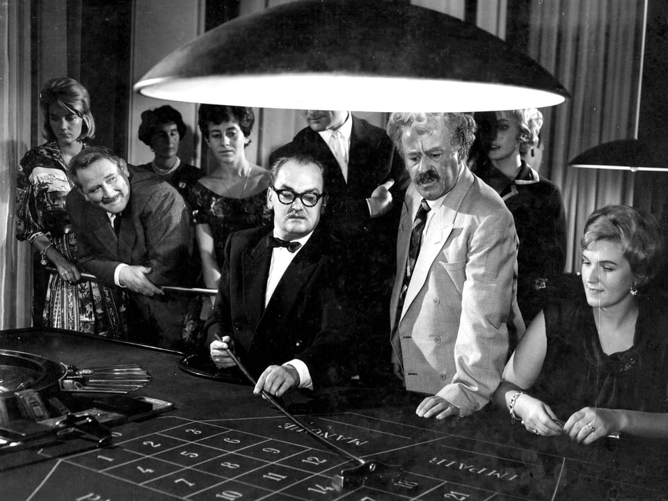 Szene tun um einen Glücksspieltisch in einem Kasino. Ein Mann spielt gerade. Männer und Frauen schauen ihm zu.