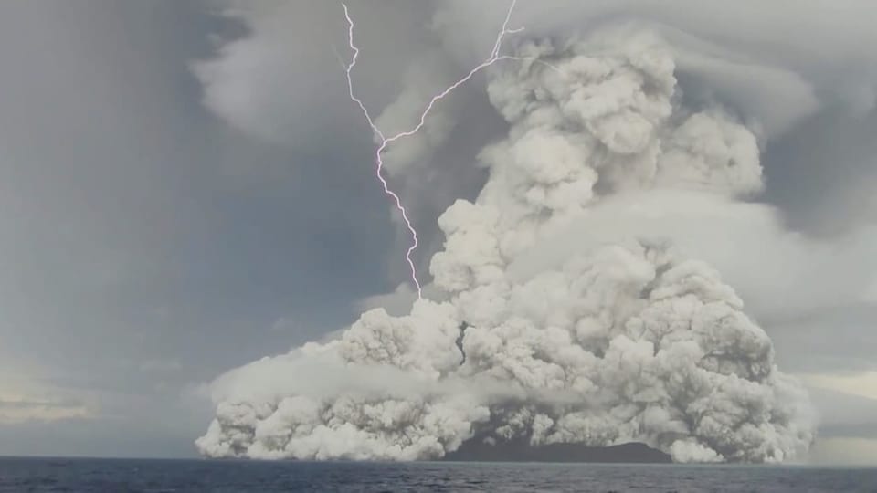Über einem Vulkan ist eine grosse graue Aschewolke zu sehen. 