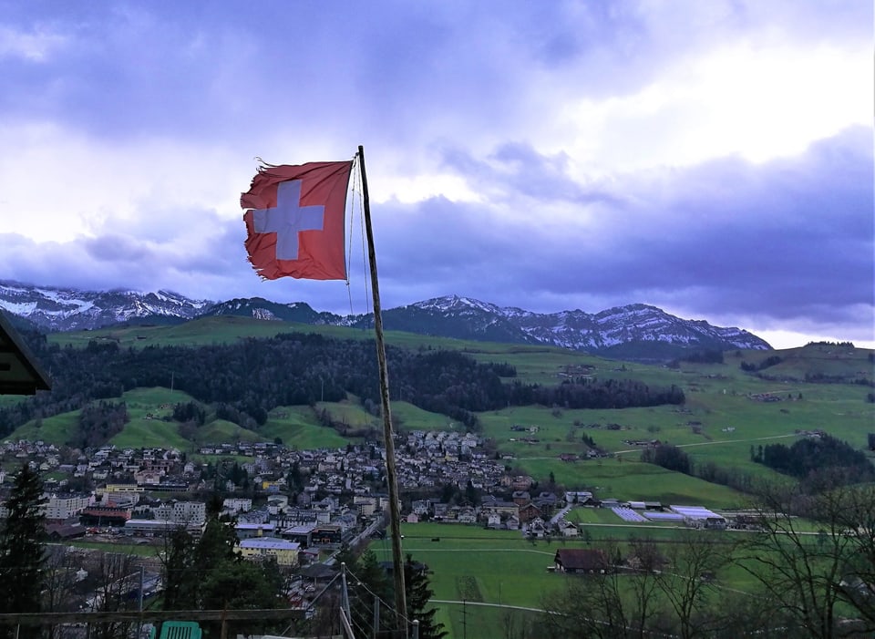 Zerrissene Schweizer Fahne. Im Hintergrund die Pilatuskette.