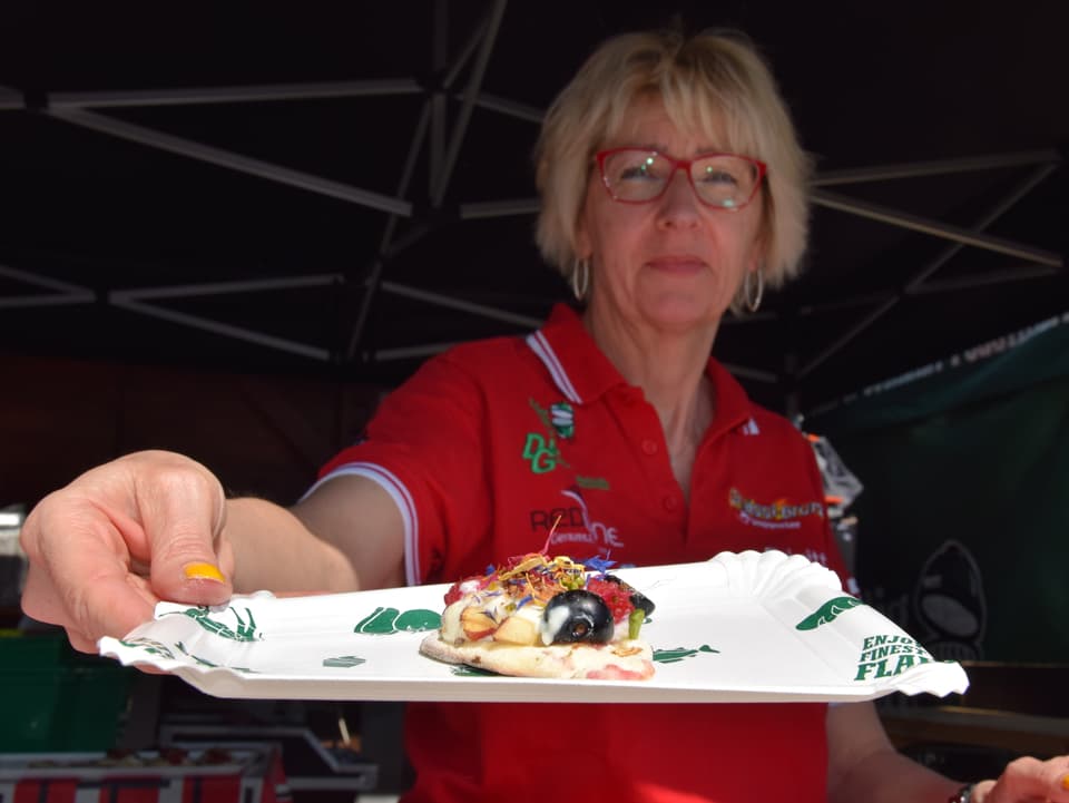 Frau präsentiert Teller mit Mini-Pizza