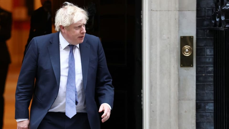 Boris Johnson trägt einen Anzug und geht aus einer Tür.