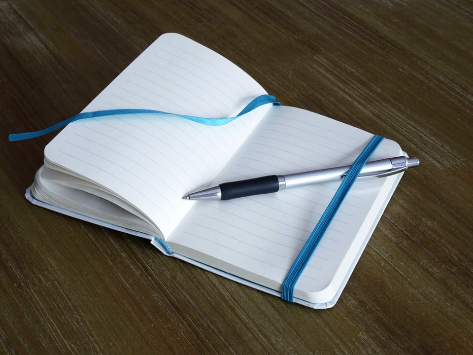 Ein leeres Notitzbuch mit einem Kugelschreiber.