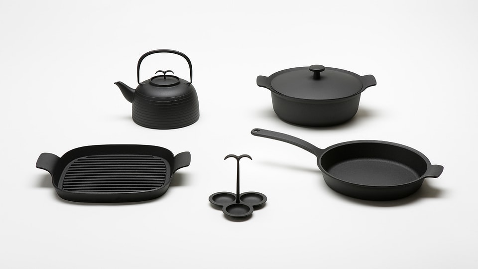 Schwarze Kochware aus Gusseisen: diverse Pfannen und ein Teekocher.