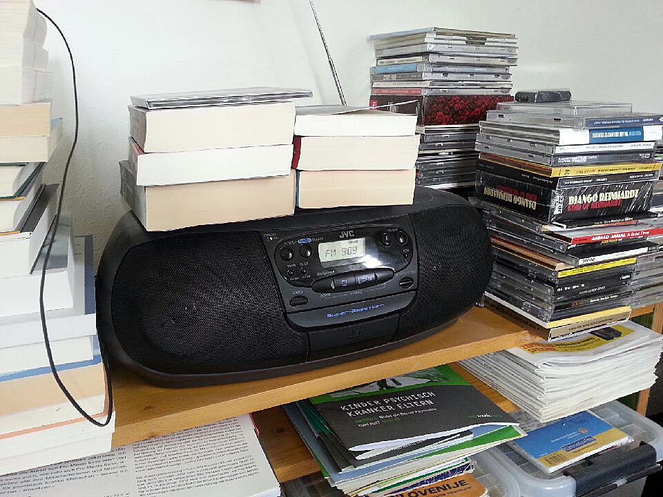 Holzgestelle mit Radio, Büchern und CDs.