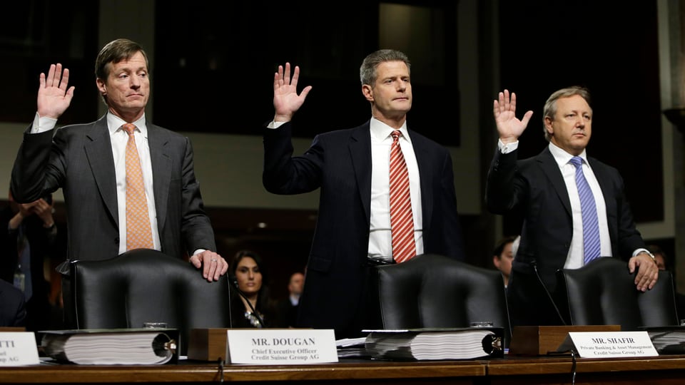 Drei Männer stehen mit erhobener rechter Hand hinter ihren Stühlen.