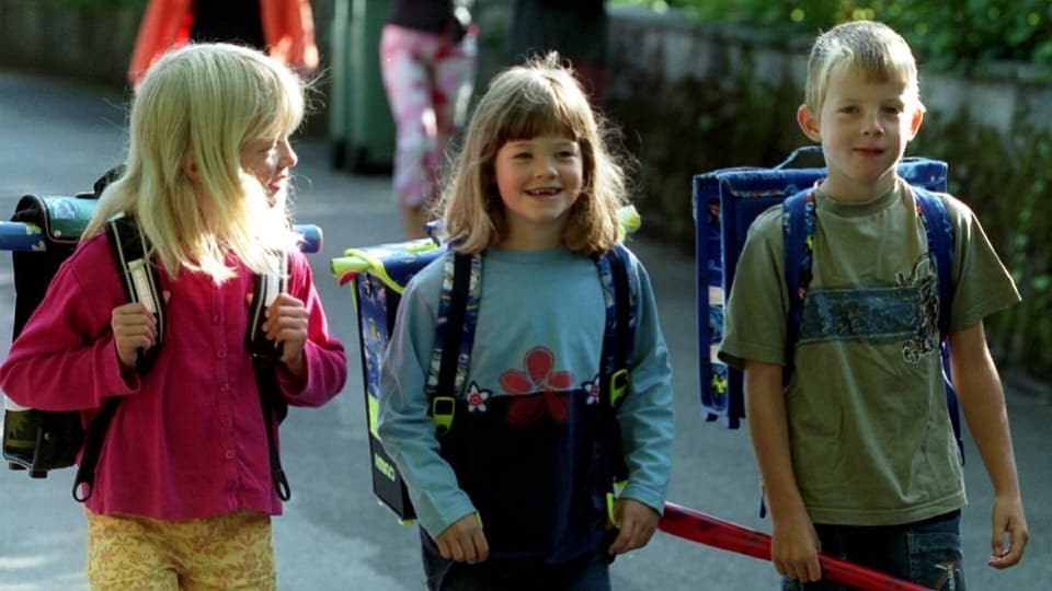 Drei Schulkinder mit Schulsack.