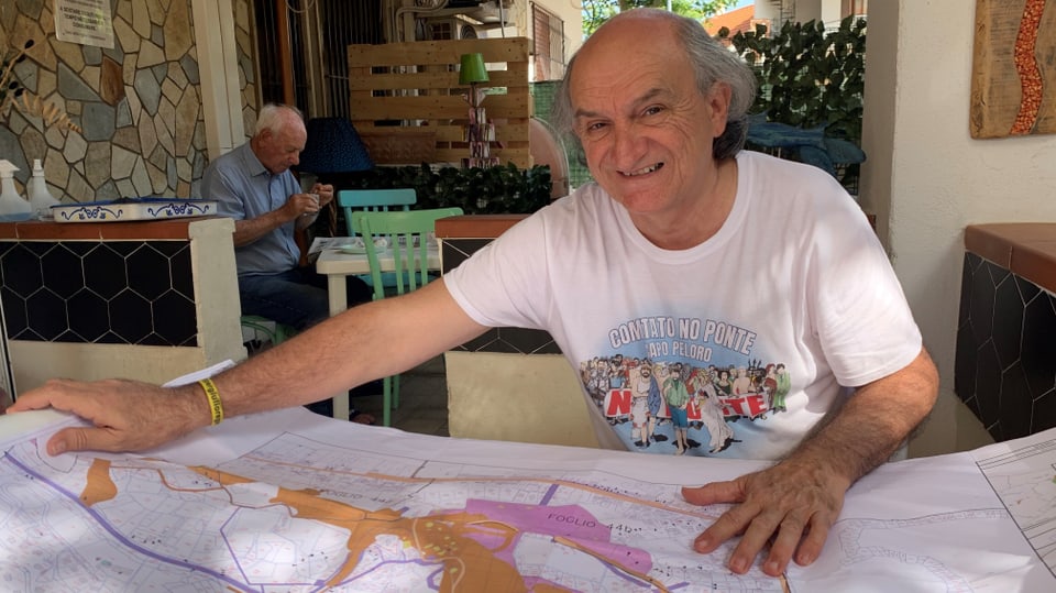 Daniele Ialacqua hält eine Landkarte ausgebreitet über dem Tisch.