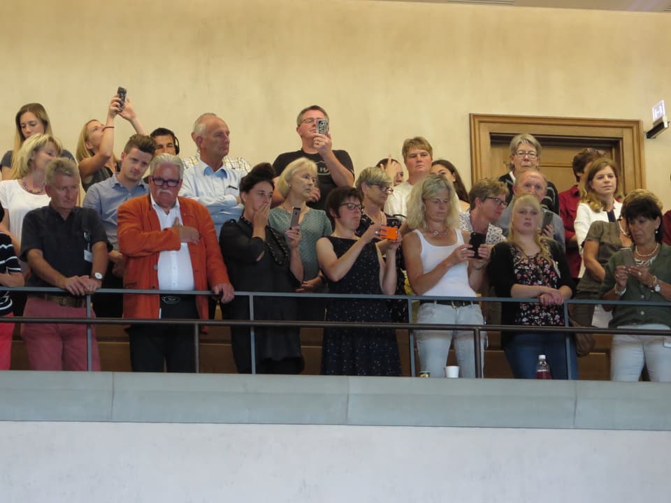 Publikum auf der Tribüne, viele fotografieren mit ihrem Smartphone