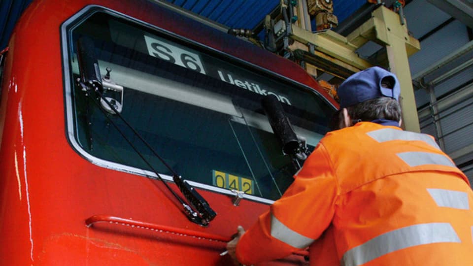 Ein SBB-Arbeiter putzt die Frontscheibe einer S-Bahn-Lokomotive.