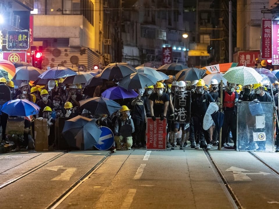 Masse auf der Strasse mit Schirmen