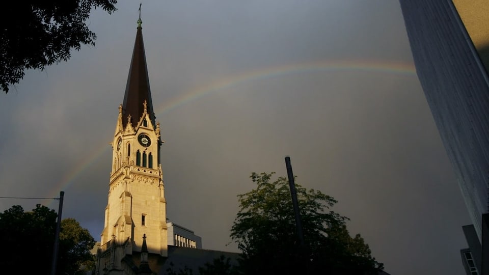 Kirchturm mit Regenbogen im Hintergrund