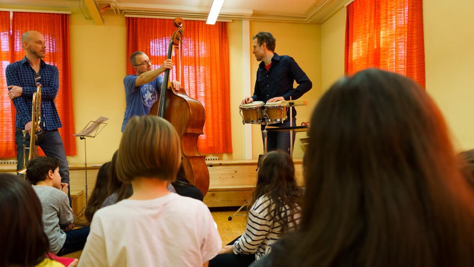 Musikexperten zeigen den Schulkindern den Umgang mit den Musikinstrumenten.