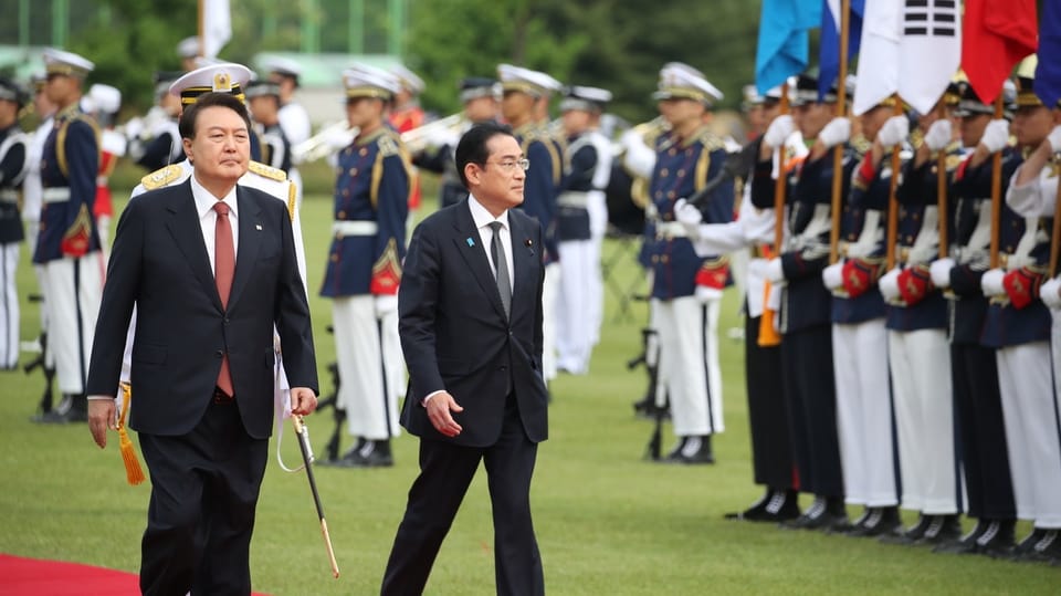 Die beiden Staatsoberhäupter laufen auf einem roten Teppich gemeinsam, während eine Eröffnungszeremonie vonstatten geht.