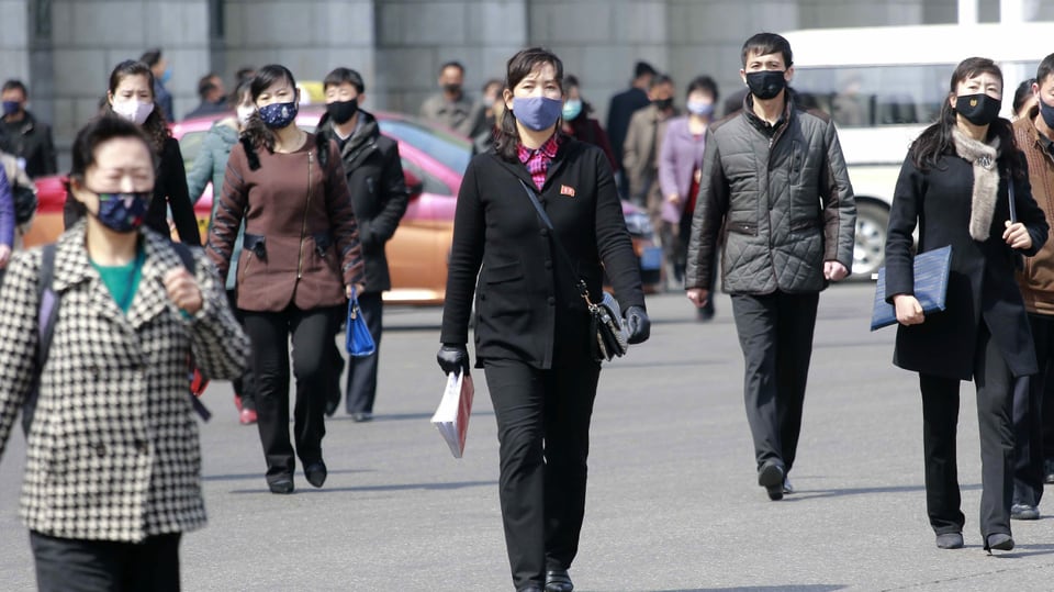 Nordkoreanerinnen und Nordkoreaner tragen auf der Strasse Masken