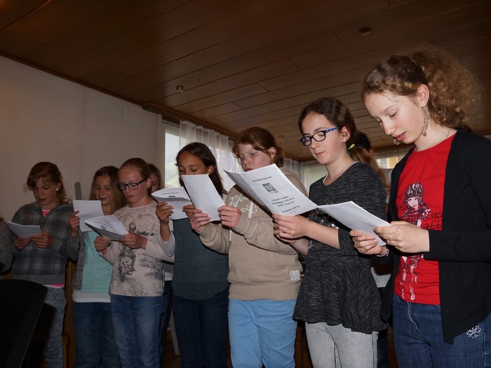 Mädchen singen ab Notenblättern.