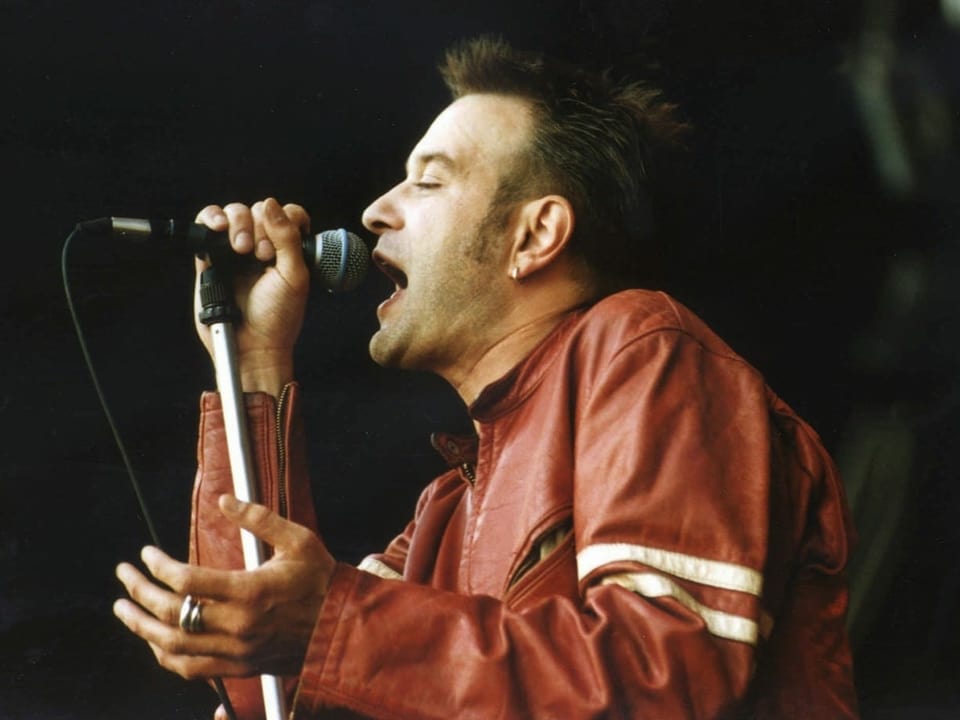 Ein Mann in roter Lederjacke singt.