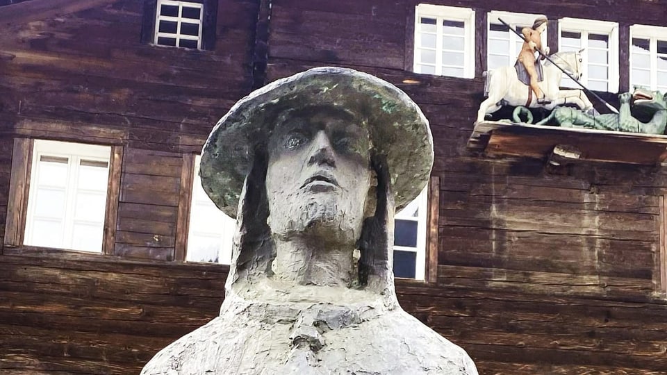 eine Statue vor einem Bauernhaus