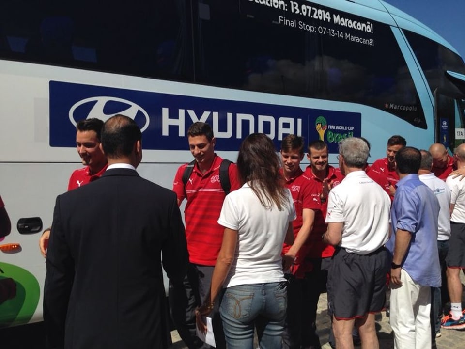 Schweizer Spieler, die eben aus dem Bus gestiegen sind, schütteln Hände.