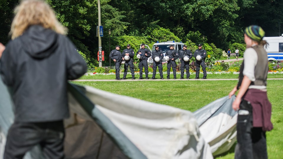 Globalisierungsgegner bauen am Montag im Hamburger Stadtpark ein Protestcamp auf. Im Hintergrund stehen Polizisten.