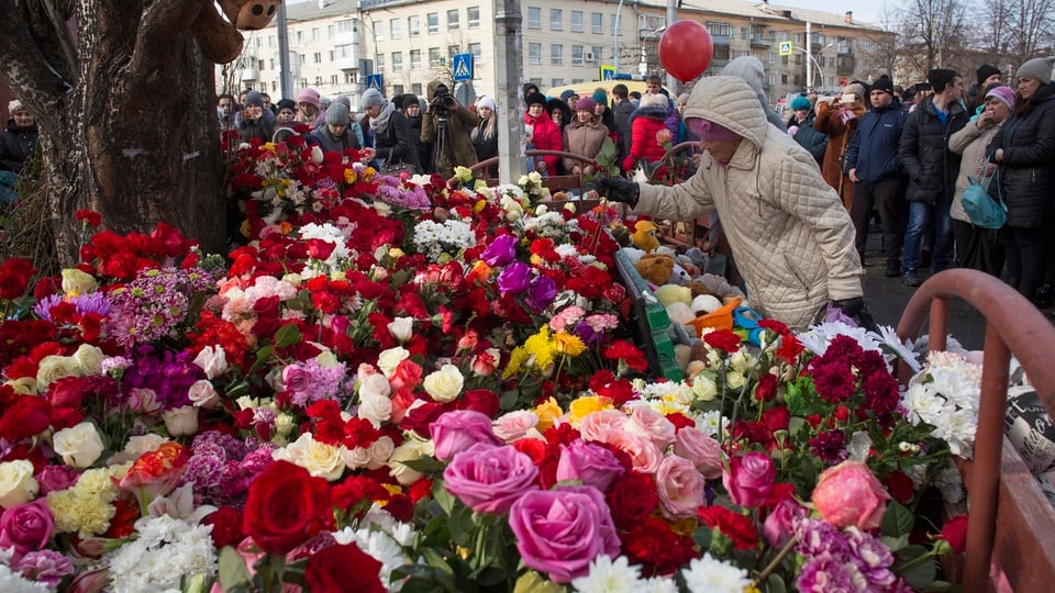 Menschen legen Blumen für die Opfer nieder.