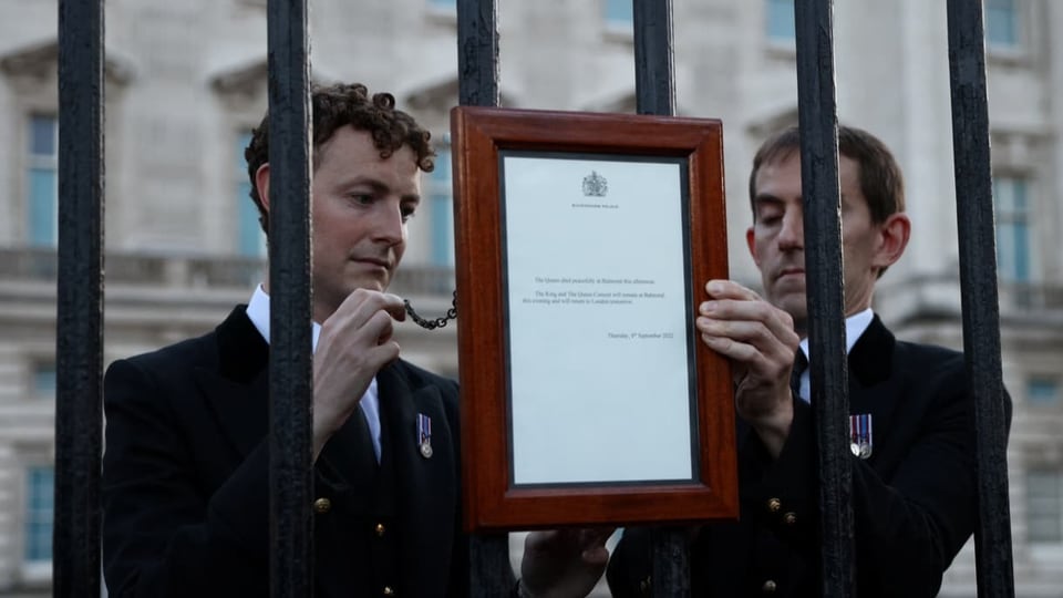 An einem Zaun vor dem Buckingham-Palast bringen Mitarbeiter ein Schild an, das den Tod von Königin Elizabeth verkündet.