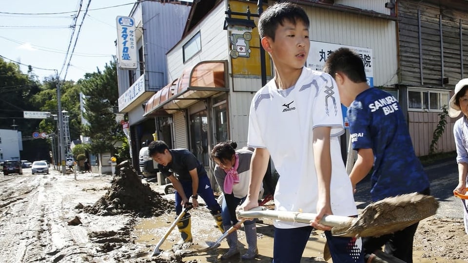 Studenten und Bewohner schaufeln Dreck, während die Stadt vom Taifun Hagibis in Marumori überflutet wird.