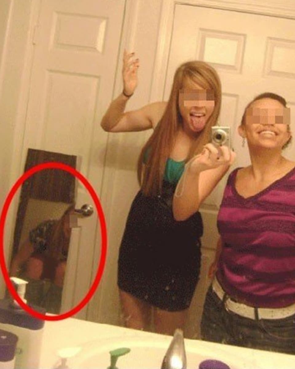 Ein Selfie, bei dem eine dritte Frau im Spiegel zu sehen ist – auf dem Klo. 