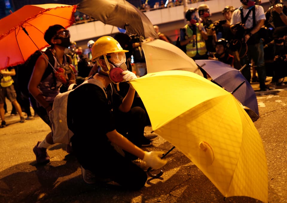 Ein Demonstrant mit Maske und Regenschirm.