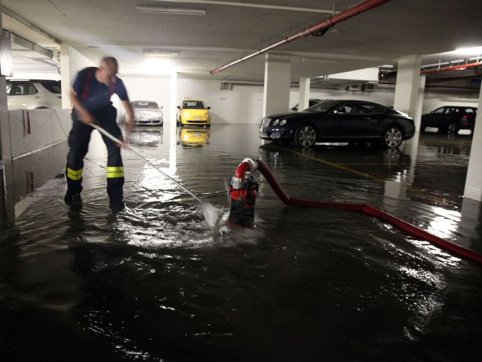 Feuerwehr pumpt eine Garage aus, die mit Wasser überflutet ist.