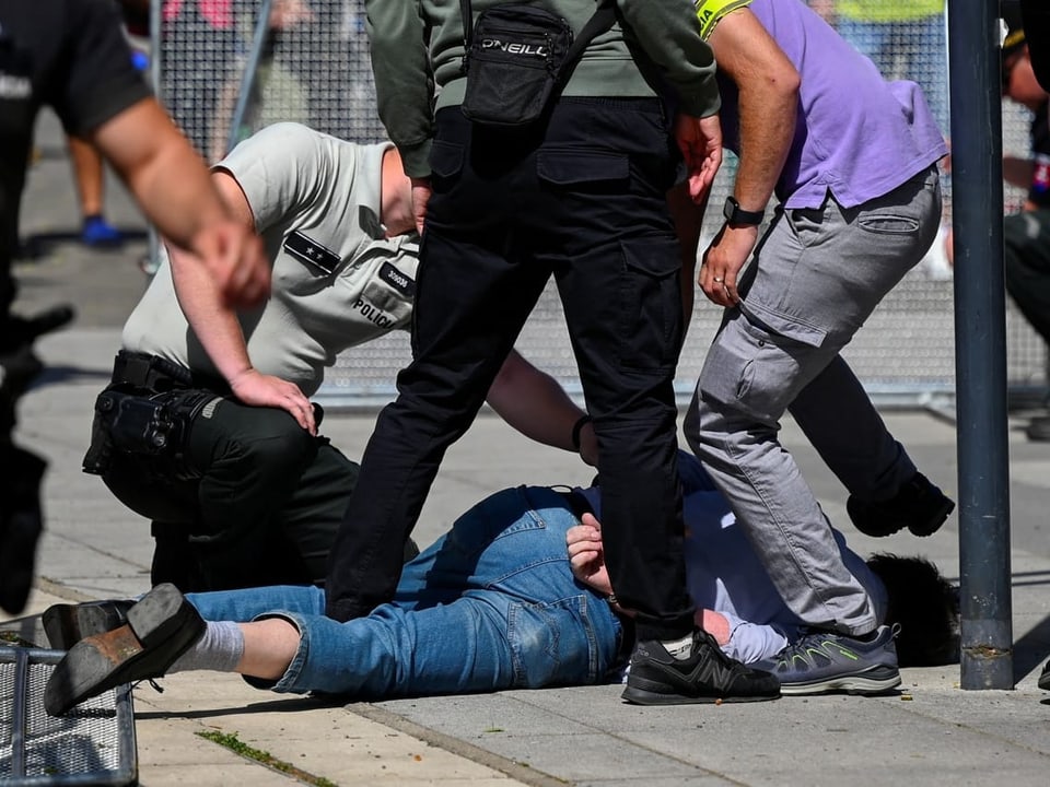 Polizisten halten Person am Boden fest.