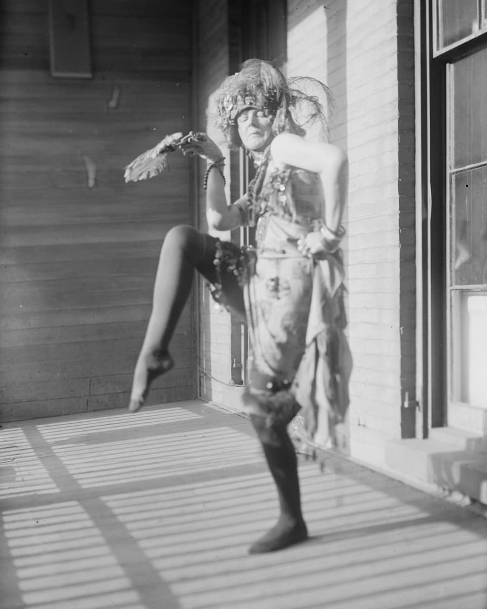 Schwarz-weiss-Bild einer Frau in Kostüm, die ein Bein hebt.