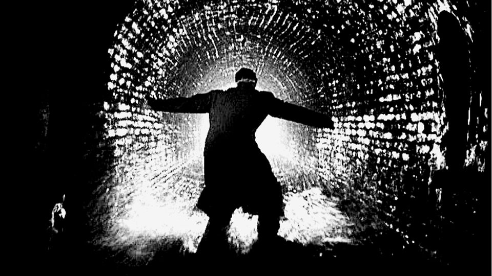 Mann mit ausgestreckten Armen im Gegenlicht in einem Tunnel