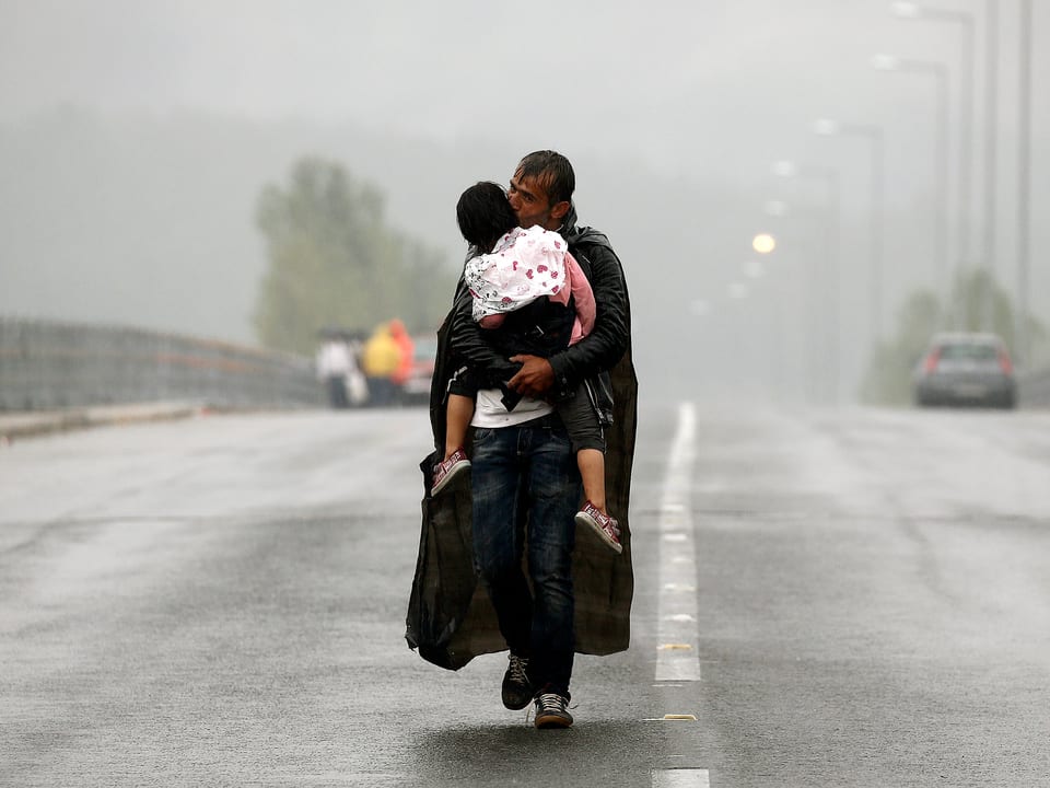Ein syrischer Flüchtling gibt seiner Tochter einen Kuss, während er in strömendem Regen zur mazedonischen Grenze läuft. 