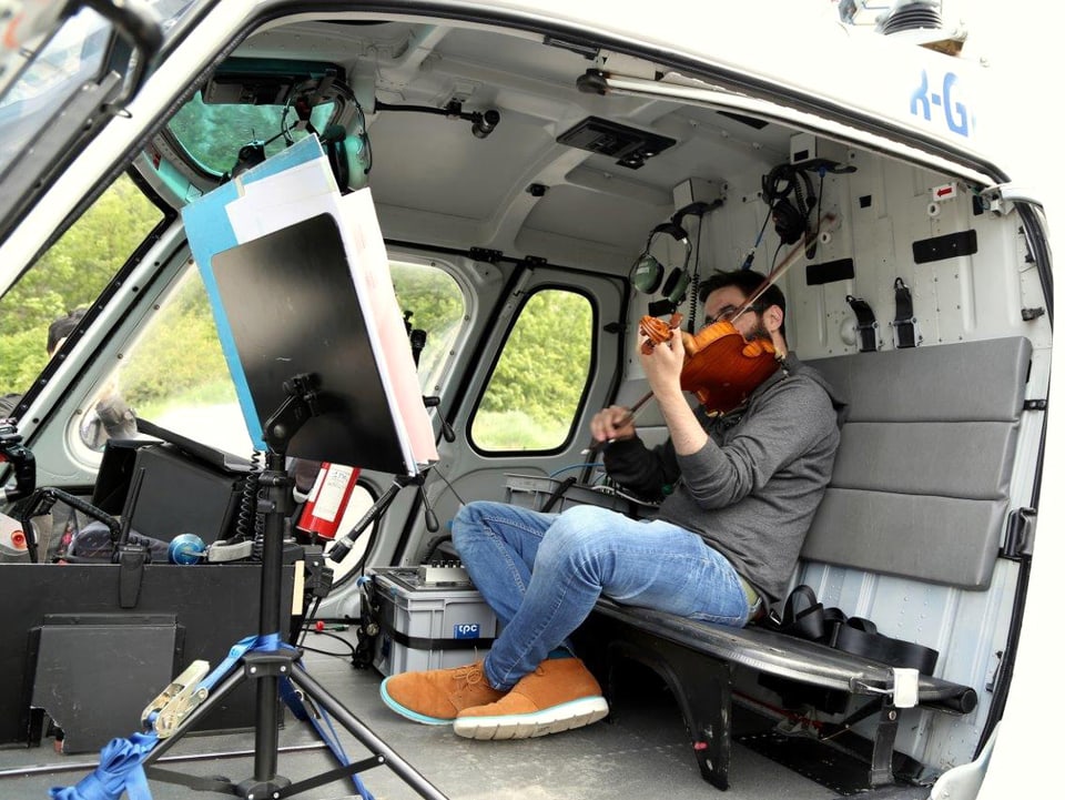 Ein Geiger sitzt in einem Helikopter und spielt Geige.